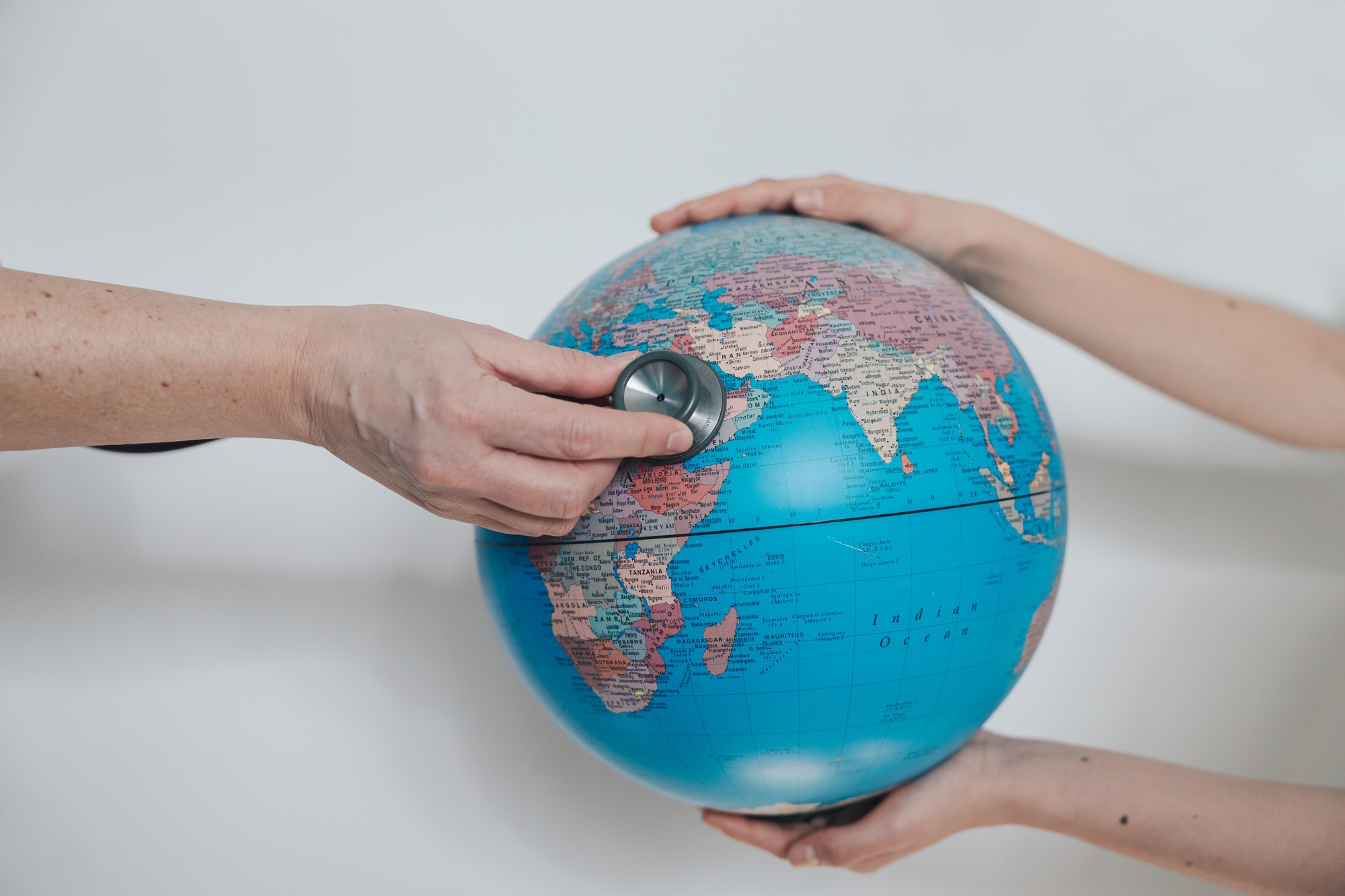 girl holds planet earth globe and woman explores with stethoscope